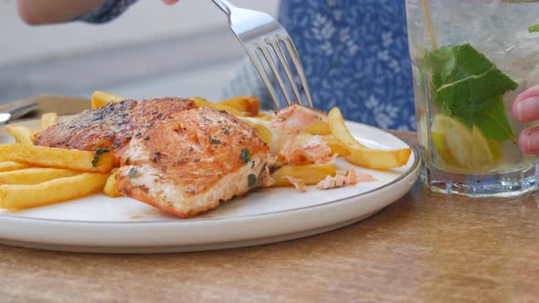 A Huge Piece of Red Salmon Fish is Grilled Next to French Fries and a Slice of Lemon