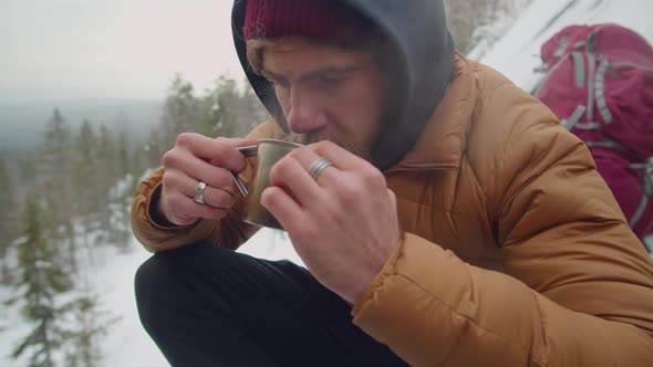 Man Drinking Hot Tea while Camping in Mountains