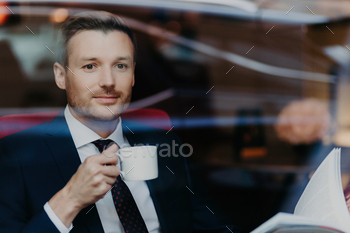 Serene businessman enjoying coffee while reading, urban café