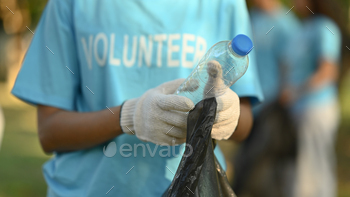 Cropped shot of female volunteer collecting garbage in public park. Charity and ecology concept.