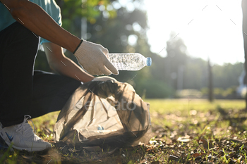 Cropped shot of volunteer collecting garbage in public park. Charity and ecology concept