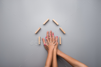 Hands of parents and two children inside the framework of a house