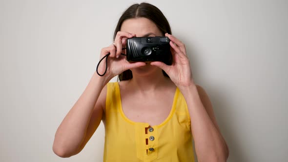 Girl Photographer in a Yellow T-shirt Takes a Soap Dish on an Old Plastic Camera