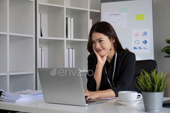 Portrait of young Asian woman working on laptop in modern office Perform accounting analysis, report