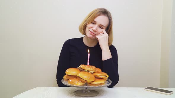a Woman Makes a Wish and Blows Out a Candle on a Hamburger Cake