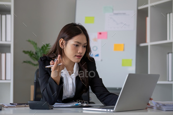 Portrait of young Asian woman working on laptop in modern office Perform accounting analysis, report