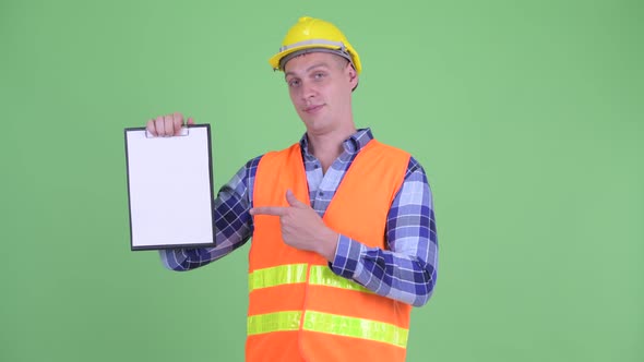 Happy Young Man Construction Worker Showing Clipboard and Giving Thumbs Up