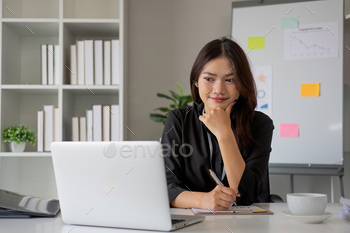 Portrait of young Asian woman working on laptop in modern office Perform accounting analysis, report