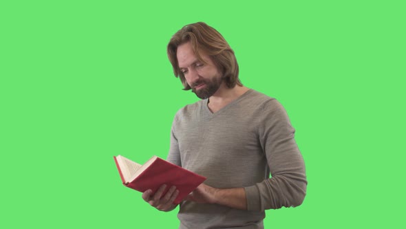 Intelligent Caucasian Man Closing Book in Red Cover and Smiling at Camera. Portrait of Smart Adult