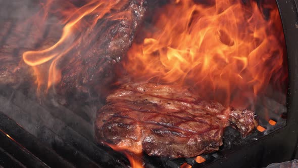 Searing and flipping ribeye steaks on grill
