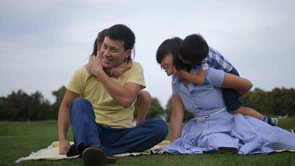 Cute Asian Siblings Embracing Parents in Nature