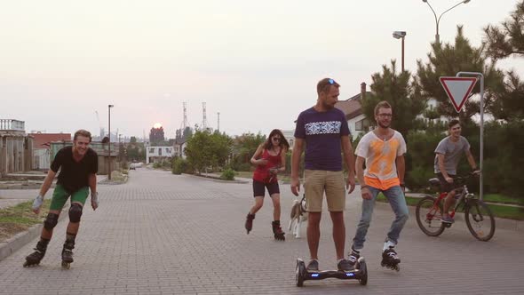 Five Friends with Husky Dog Rollerblading Riding Bicycle and Gyroscooter Outside Having Fun in