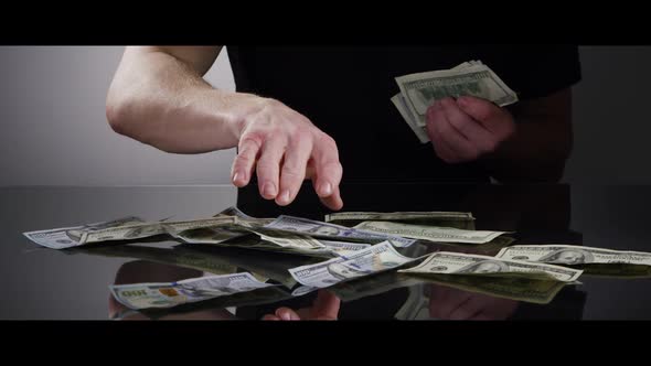 Hands of a man picking up $100 Bills off of a Reflective Surface - MONEY 0034