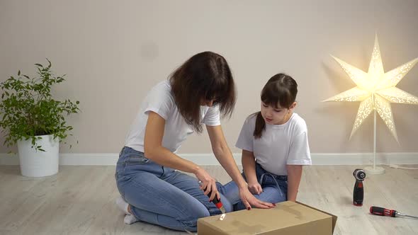 Happy Family Mother and Daughter Unpack New Wooden Furniture Together