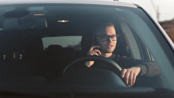 A Man is Sitting in a Car and Talking Emotionally on the Phone