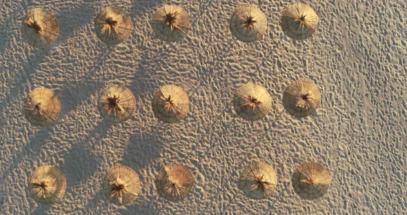 Top down view of beach straw umbrellas at sunrise on the beach.