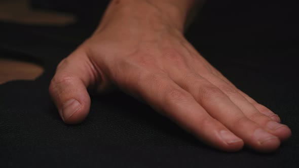 Close Up Man's Hand Move Slowly on Black Fabric in Workshop