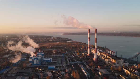 Factory chimneys producing smoke at sunrise, aerial view.