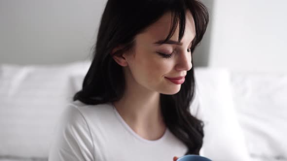 Pregnant Young Woman Drinking Tea And Sitting On Bed At Home