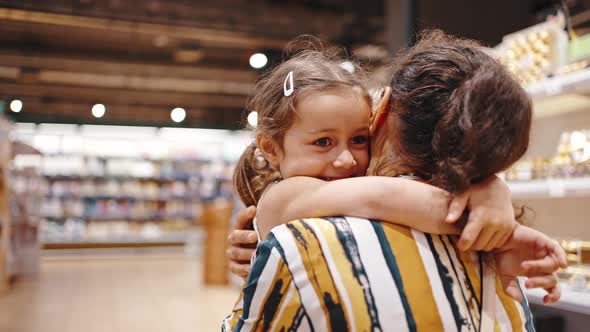 Close Portrait of a Happy Preschool Girl Hugs Her Mom in the Supermarket