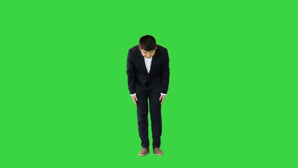 Asian Man in Office Suit Making a Bow on a Green Screen Chroma Key