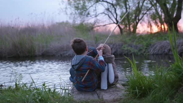 Family Weekend, Fishermen Little Brothers Sit on Pier and Fish with a Wooden Fishing Rod, Back View