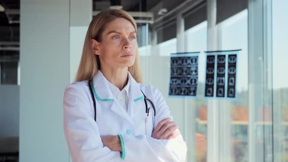 Pensive Young Female Caucasian Doctor Look in Window Folding Hands Thinking