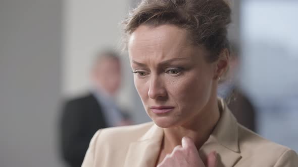 Closeup of Panicked Stressed Caucasian Woman in Office with Blurred Coworkers at Background