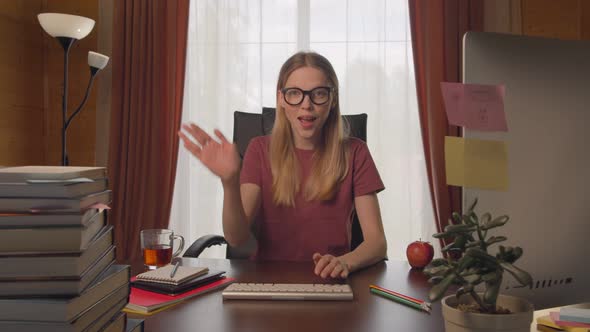 Young Woman at Table Typing on Keyboard, Calling on Video Link, Shows Gesture Stop