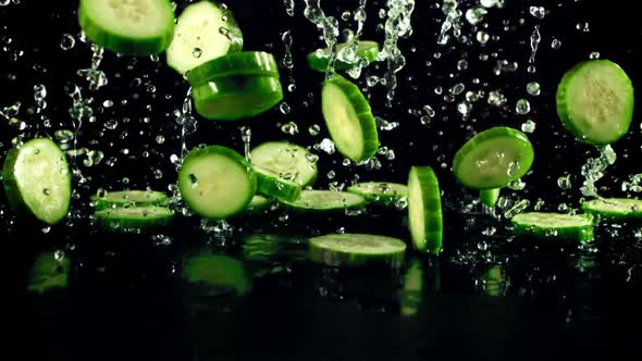 Pieces of Fresh Cucumbers with Drops of Water Fly Up and Fall
