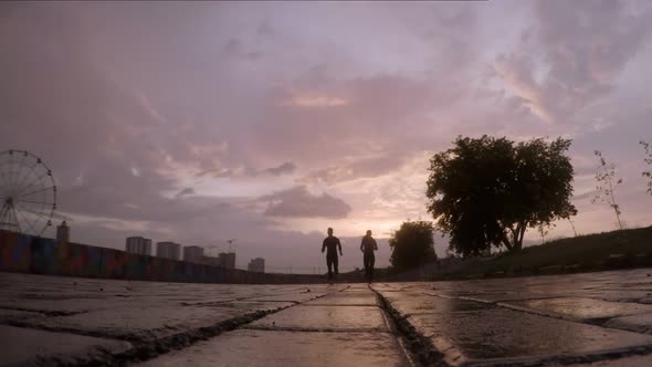 Couple Running on Wet Asphalt at Sunset