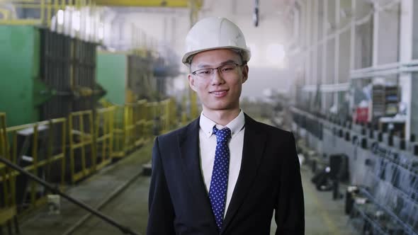 Successful Asian senior executive staying at factory