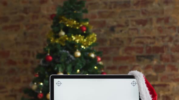 Video of computer with santa hat over christmas tree