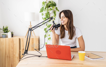 Professional female podcaster recording podcast on computer from home studio
