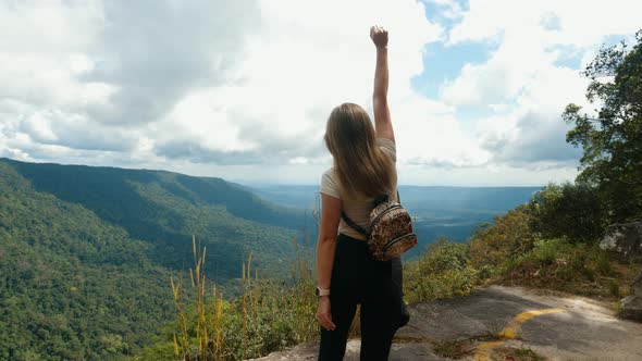 Young Active Successful Woman Raising Her Arms Up Standing on Top of Mountain