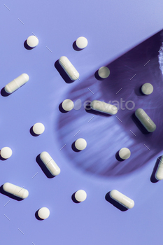 Various vitamins and pills on a purple background. Medicine, treatment and health.