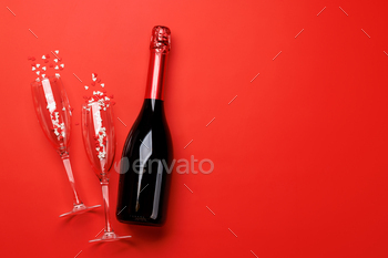 Champagne glasses and bottle on a red background with text space