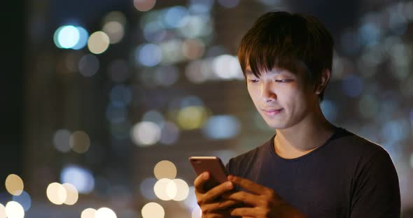 Man use of mobile phone in city at night