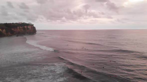 Aerial view over the beach with lots of people surfing on strong waves in Bali