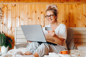 Online shopping, e-commerce concept. Happy adult woman using laptop and holding credit card
