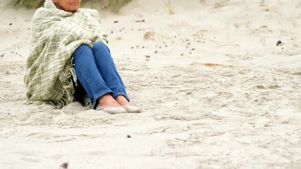 Thoughtful retired woman sitting on the beach