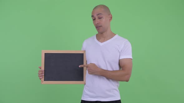 Serious Bald Man Holding Blackboard and Giving Thumbs Down