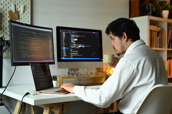 Concentrated male web developer working with coded data on computer screen.
