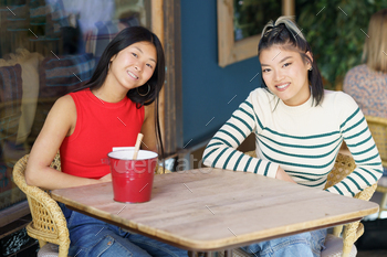 Happy Asian girls chatting in cafe together