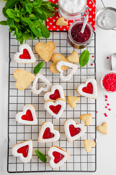 Heart-shaped cookies with berry jam and powdered sugar with mint leaves. Cookies for Valentine's Day