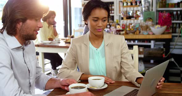 Businesspeople using a laptop while having cup of coffee