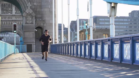 Slow motion shot of man with headphones walking on tower bridge