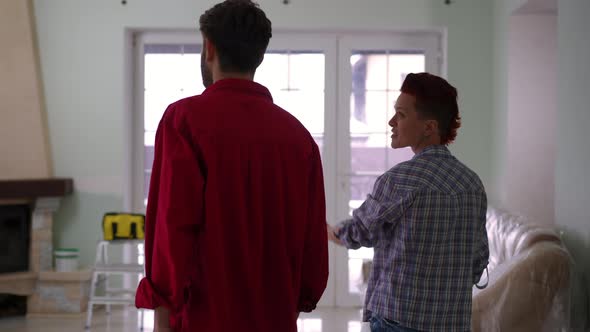 Back View Positive Caucasian Man and Woman Entering Living Room in New House