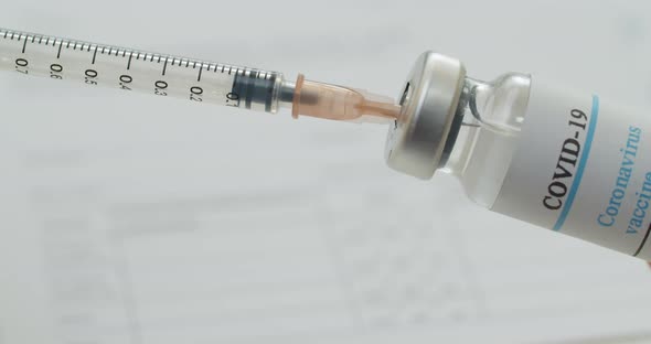 Close Up of Hand Filling a Syringe with Liquid From a Vial with a Label Reading Covid19 Vaccine