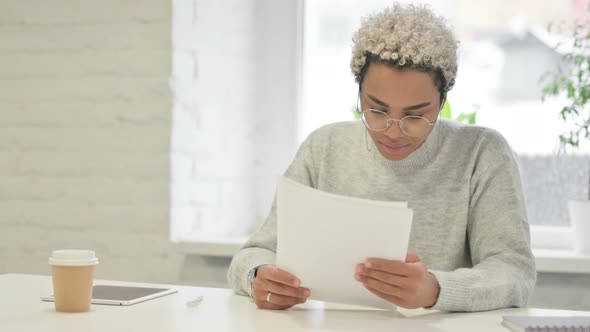 African Woman Celebrating Success While Reading Documents in Office